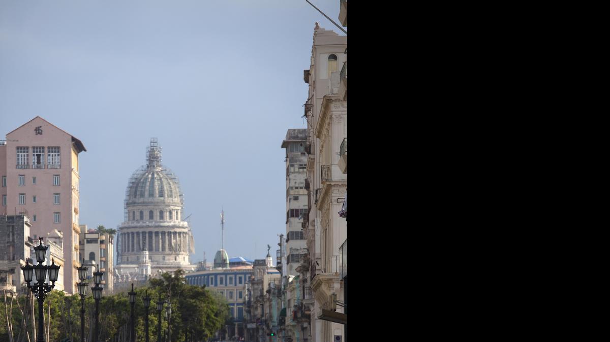 
Un automóvil norteamericano antiguo se destaca en una calle de La Habana, con el Capitolio, en proceso de reparación, al fondo.
