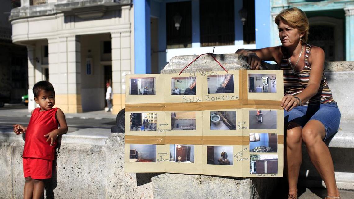 Una mujer muestra fotos de su casa en venta en La Habana, en el 2013. Durante muchos años los cubanos no podían comprar ni vender inmuebles, pero las reformas del gobernante Raúl Castro han permitido la aparición de un mercado de bienes raíces en la isla.