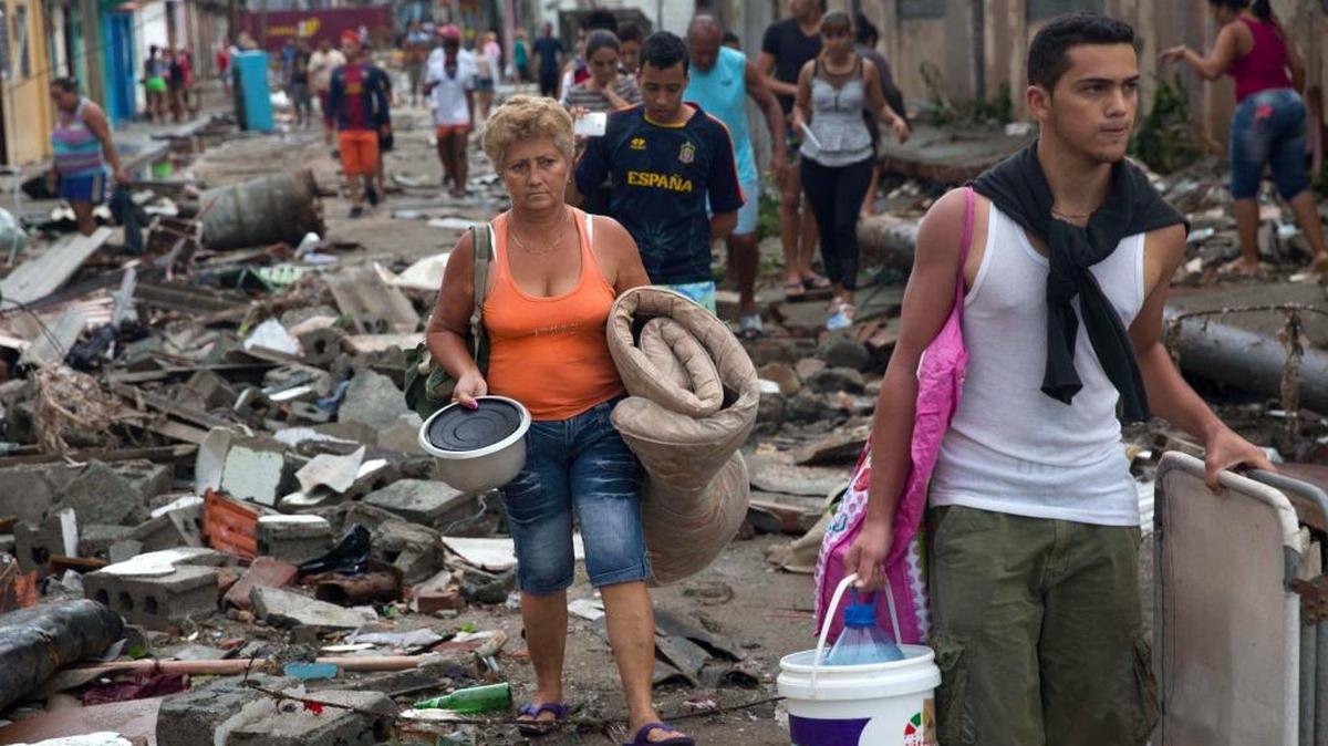 Damnificados cruzan con sus pertenencias una calle de la ciudad de Baracoa, en el extremo oriental de Cuba, el miércoles, tras el paso del huracán Matthew.