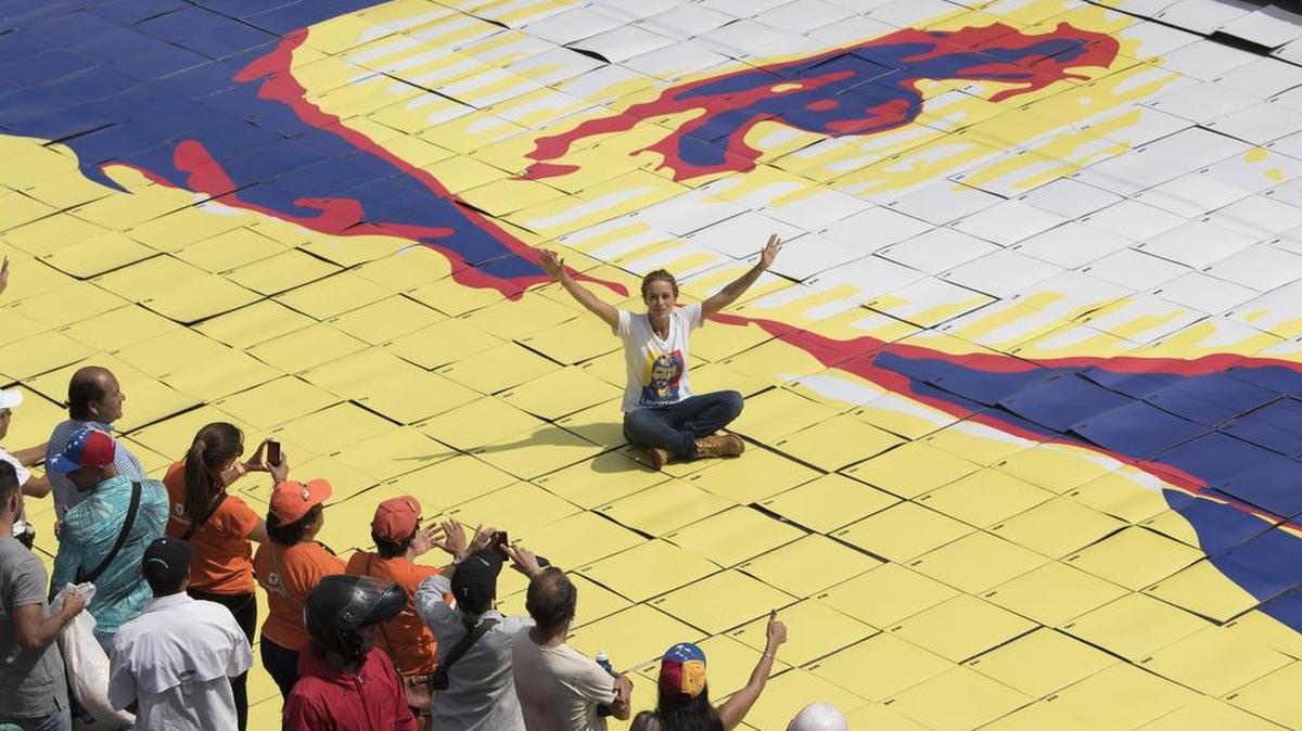Lilian Tintori, esposa del líder opositor venezolano Leopoldo López, se sienta sobre un enorme retrato de su esposo, durante una protesta por el encarcelamiento de López realizada en Caracas el 28 de febrero.