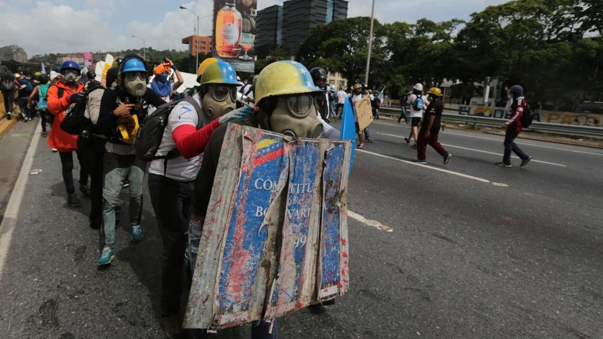 Manifestantes con un escudo decorado como la Constitución venezolana tratan de avanzar hacia el Consejo Nacional Electoral en Caracas, el 24 de mayo.