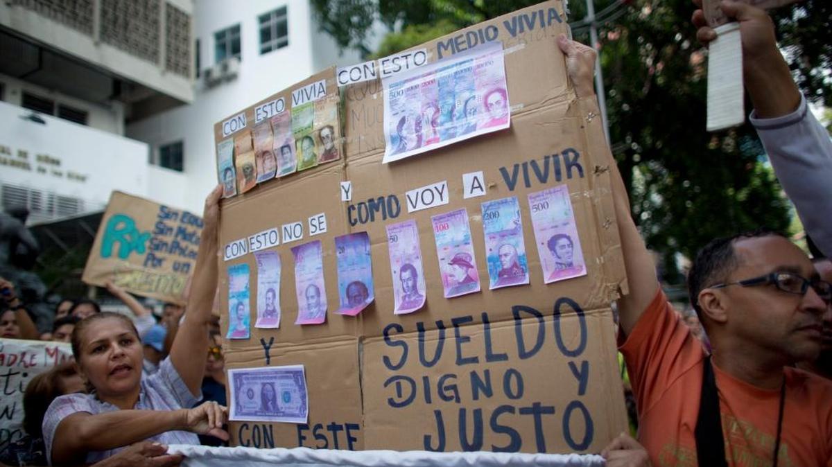 Las enfermeras muestran una pancarta de billetes falsos en protesta por la inflación que ha devaluado la moneda, en Caracas, el 16 de agosto.