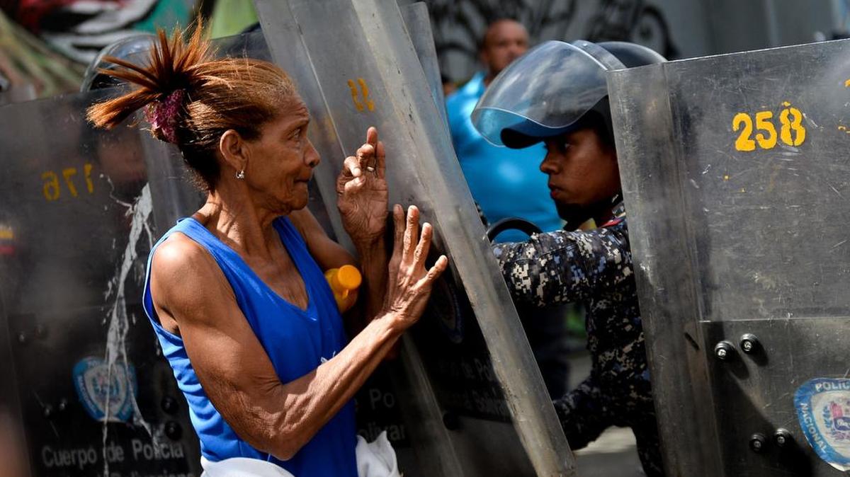 Un policía empuja a una mujer que protesta por la falta de alimentos, el 28 de diciembre de 2017 en Caracas, Venezuela.