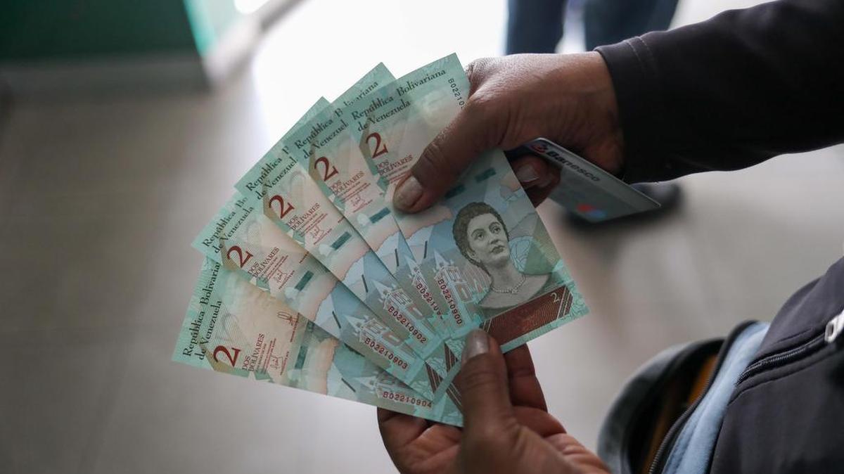 Un cliente de un banco muestra billetes del nuevo cono monetario tras retirar dinero en la entidad el 21 de agosto.