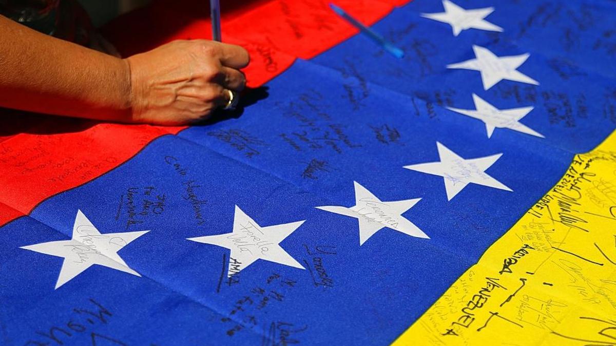 Una mujer pone su firma en una bandera venezolana a la salida de los puntos de votación en el campus oeste del Miami Dade College, el 16 de julio.