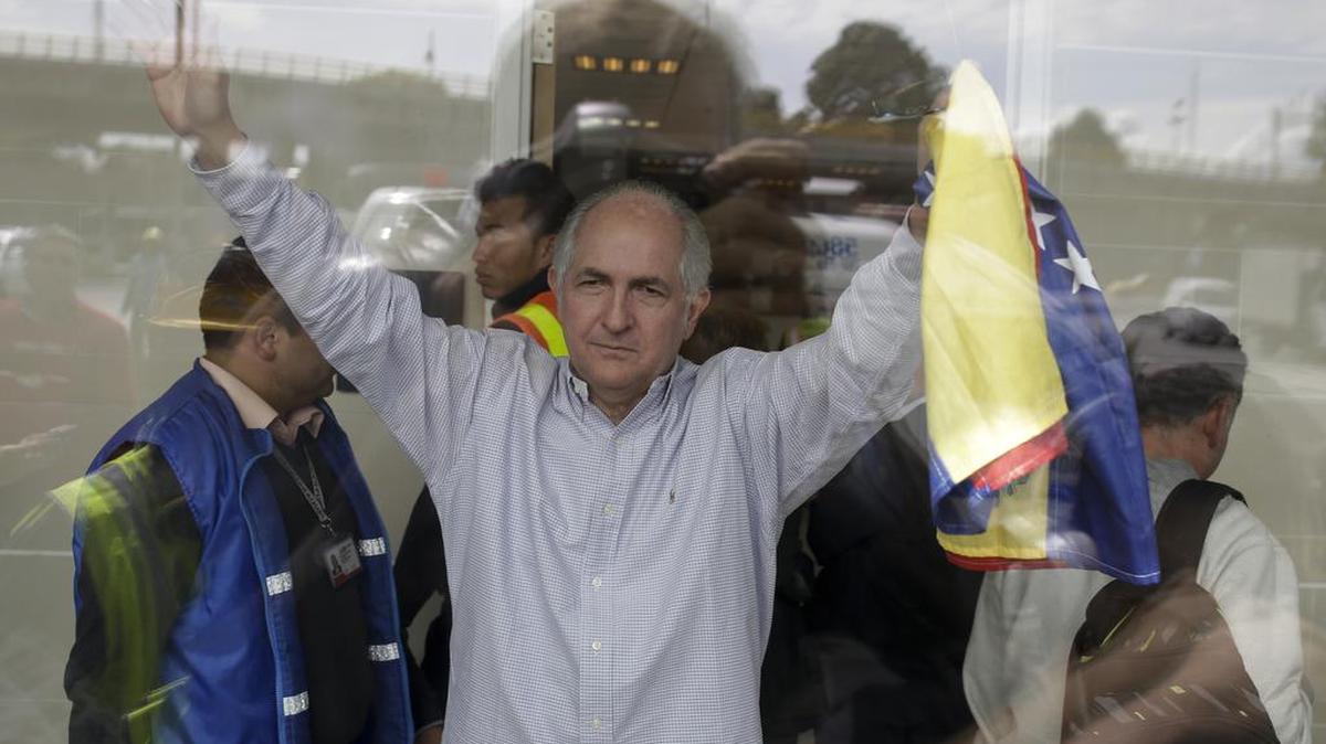 Sosteniendo una bandera venezolana, el alcalde metropolitano de Caracas, Antonio Ledezma, saluda en el Aeropuerto Internacional El Dorado, en Bogotá. Ledezma escapó de Venezuela, donde estaba bajo arresto domiciliario, el 17 de noviembre.