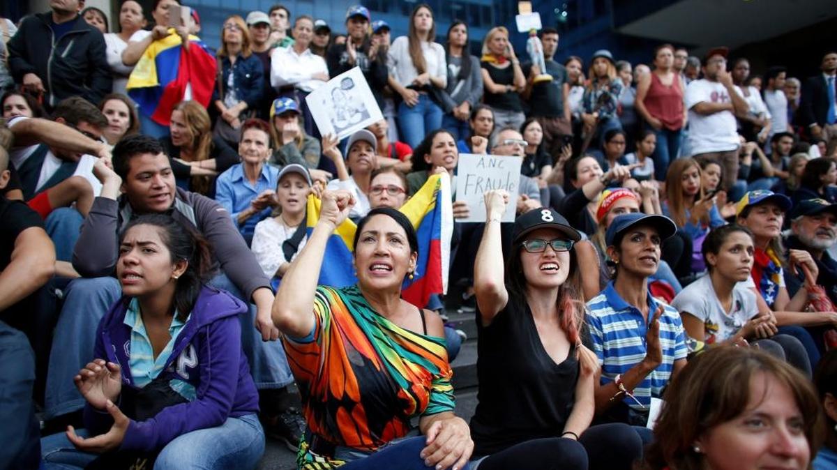Opositores al gobierno venezolano corean consignas contra el presidente Nicolás Maduro durante una vigilia en recuerdo de los caídos en las protestas.