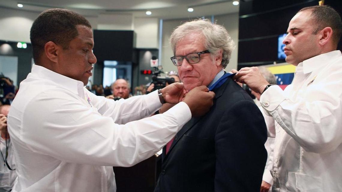 El exiliado venezolano José Colina le pone la medalla Orden del Exilio Venezolano Rómulo Betancourt al secretario general de la OEA, Luis Almagro, con Henry Clement (der.), en un homenaje a la alcaldía de Doral, el 13 de abril.