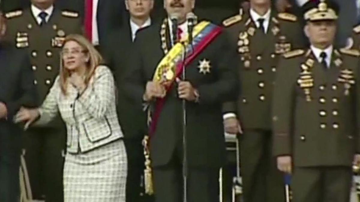 VIDEO STILL, BEST QUALITY AVAILABLE - In this still from a video provided by Venezolana de Television, Presiden Nicolas Maduro, center, delivers his speech as his wife Cilia Flores winces and looks up after being startled by and explosion, in Caracas, Venezuela, Saturday, Aug. 4, 2018. Venezuela’s government says several explosions heard at a military event were an attempted attack on President Maduro. Information Minister Jorge Rodriguez said in a live broadcast that several drone-like devices with explosives detonated near the president. He said Maduro is safe and unharmed but that seven people were injured. (Venezolana de Television via AP)