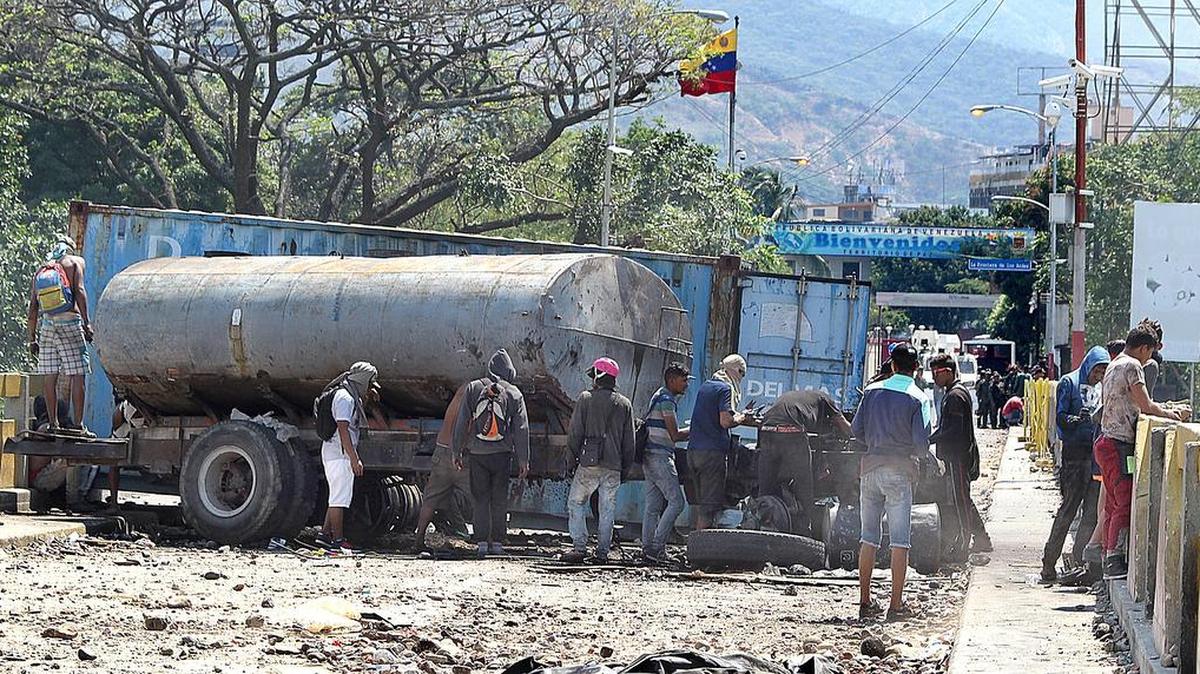 Una decena de manifestantes examinan el 25 de febrero un camión y un contenedor que bloquean el Puente Internacional Simón Bolívar, que conecta a Cúcuta, Colombia, con San Antonio, Venezuela.