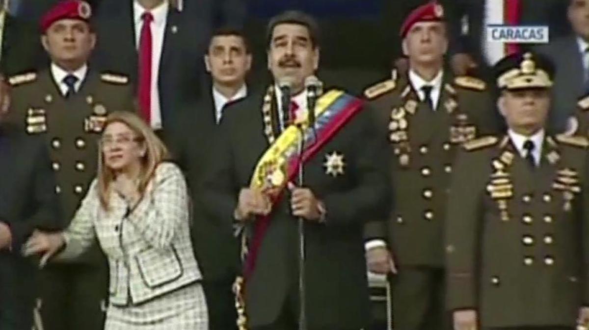 El presidente Nicolás Maduro parece imperturbable al estallar unos drones en Caracas, el 4 de agosto, mientras su esposa, Cilia Flores, mira hacia arriba con asombro.