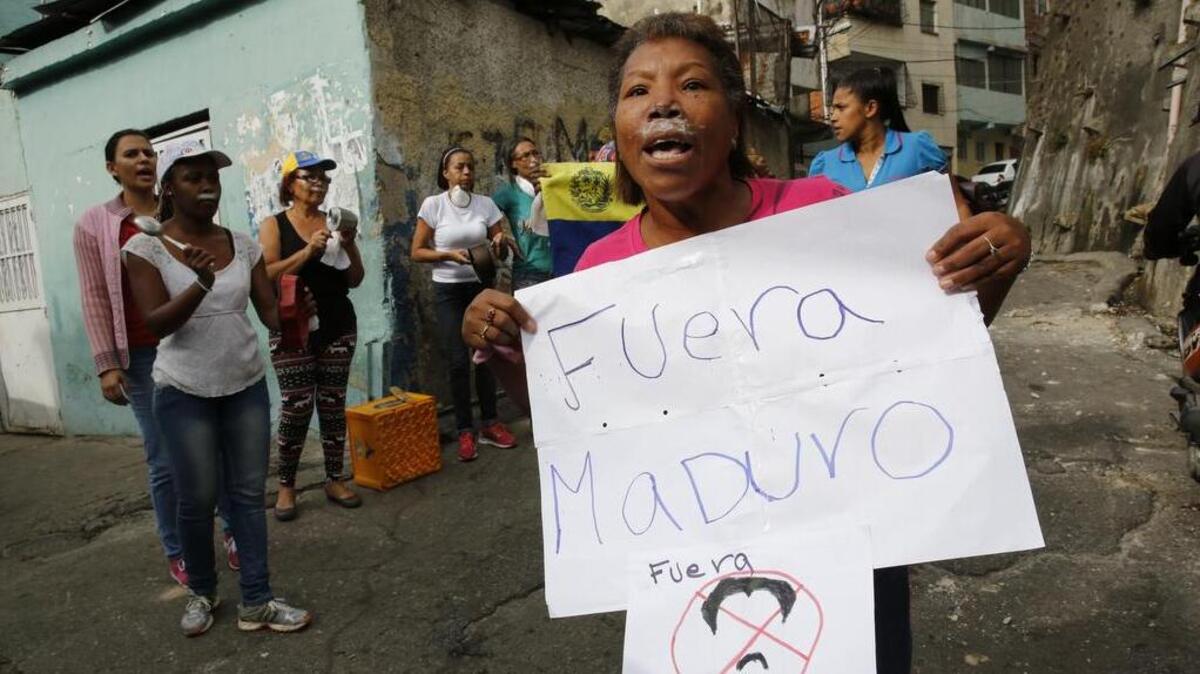 Una mujer, con crema dental bajo la nariz para limitar los efectos de los gases lacrimógenos, junto a otras personas protestan contra el gobierno de Nicolás Maduro, el lunes en un barrio de Caracas.