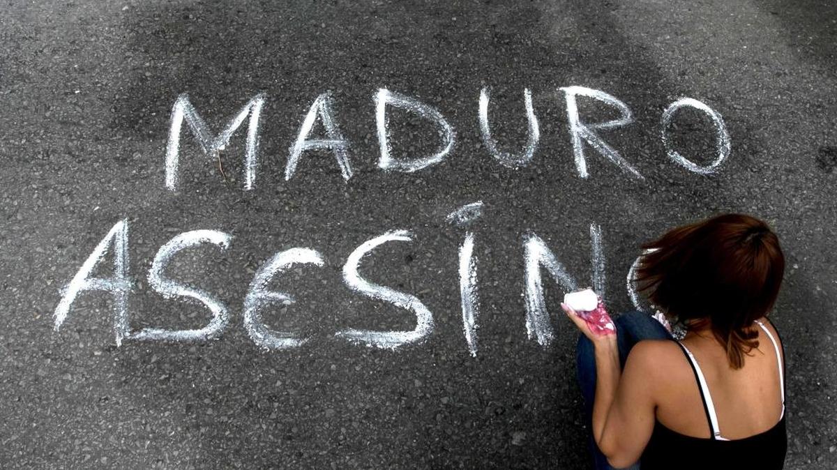 Una mujer escribe un mensaje sobre el asfalto durante una manifestación el 16 de junio, en Caracas.