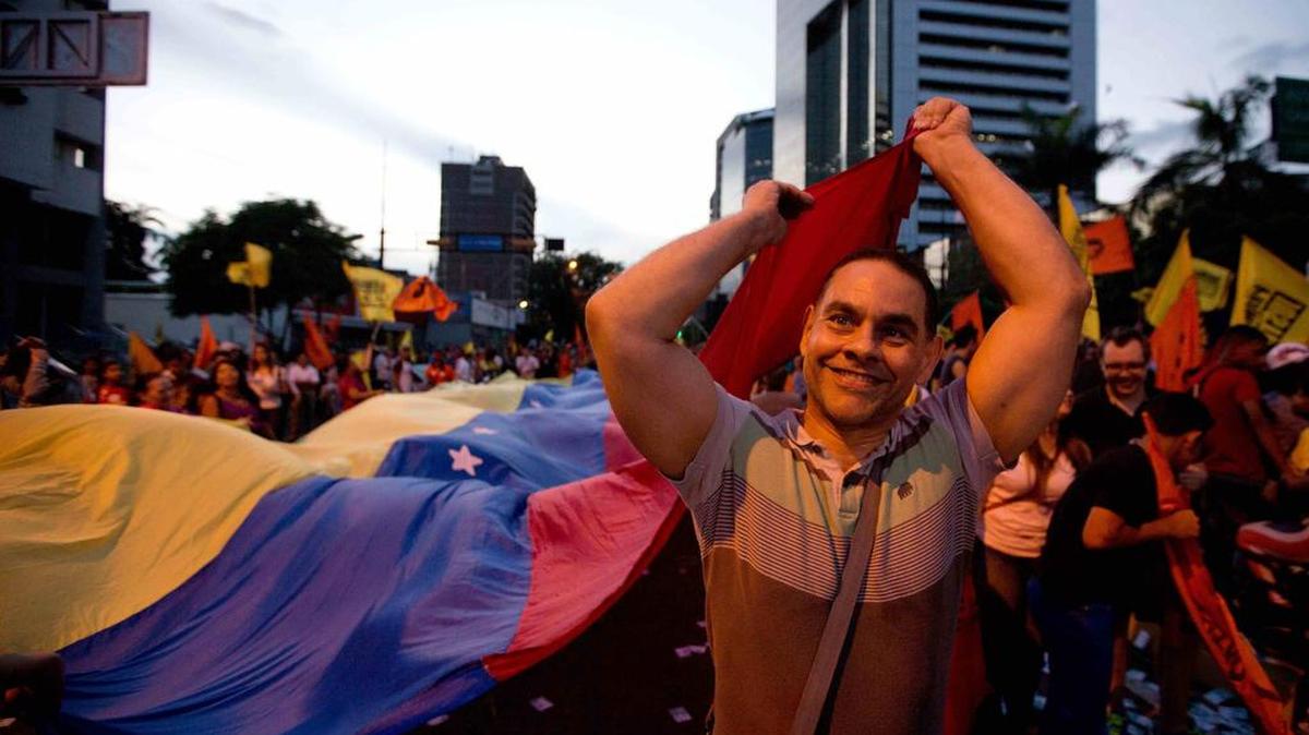 Un miembro de la oposición extiende una bandera venezolana en un acto de campaña electoral en Caracas, el jueves pasado.