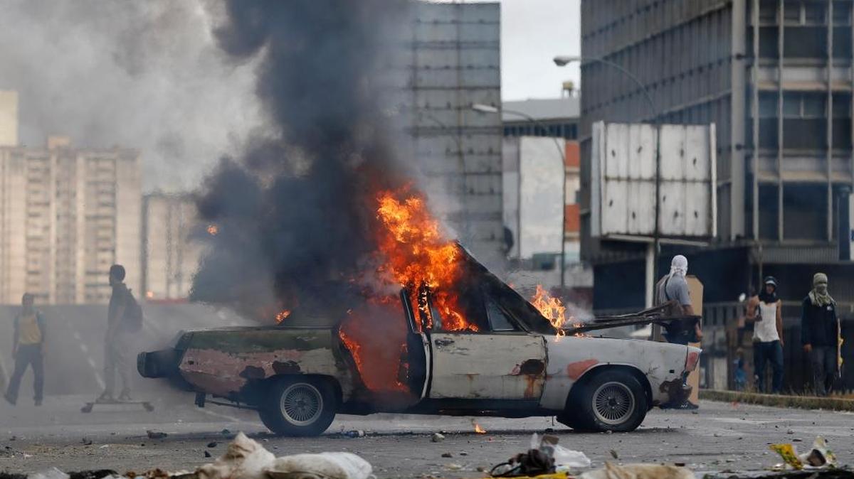 Una de las estrategias de los opositores venezolanos en las protestas es bloquear las calles, como en este caso con un auto incendiado, en Caracas, el 20 de julio.