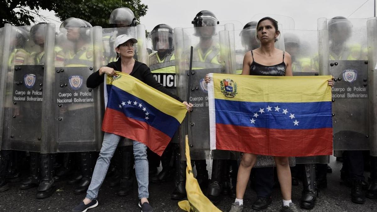 Dos manifestantes alzan banderas venezolanas frente a la policía durante una protesta de la oposición en Caracas, el miércoles pasado.