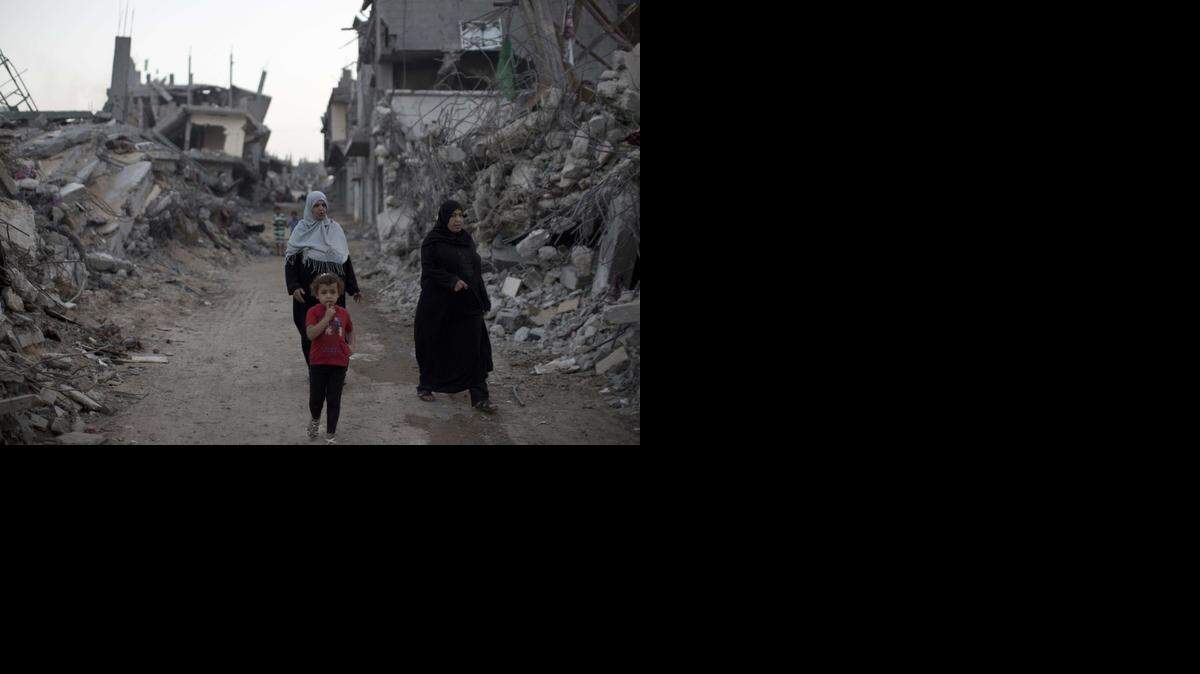 
Una niña y dos mujeres palestinas caminan a fines de septiembre entre edificios derruidos en Gaza durante el conflicto entre Israel y Hamas.
