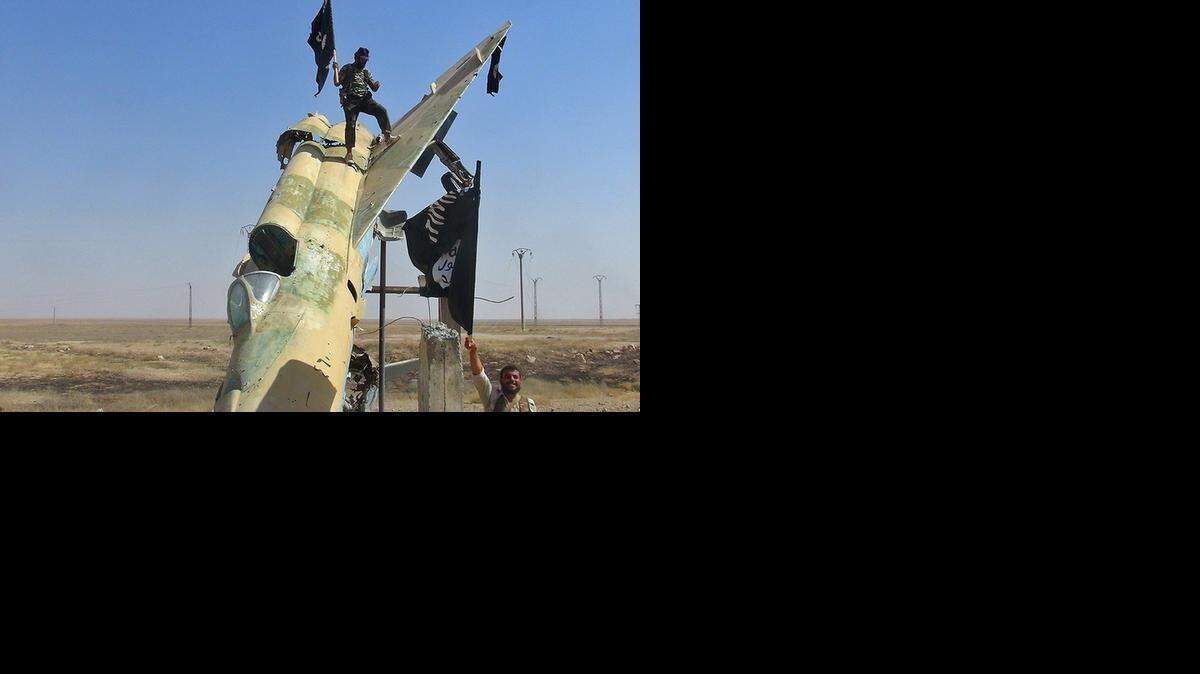 
Combatientes del Estado Islámico sirio ondean su bandera luego de una batalla en la base aérea Tabqa localizada en Raqqa, Siria.


