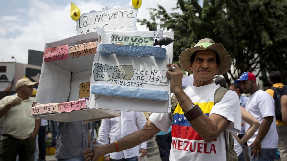 Varios manifestantes muestran cajas vacías como si fueran refrigeradores para indicar la escasez de productos, en una protesta de la oposición en Caracas realizada el 14 de mayo.