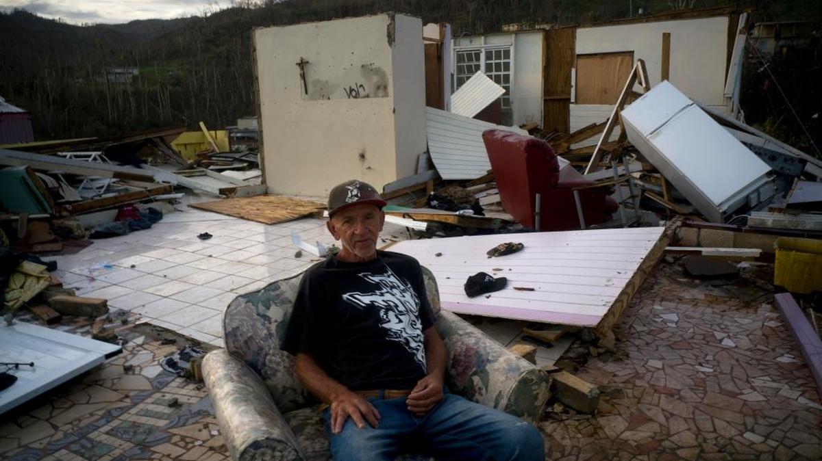 Luis Cosme se sienta entre las ruinas que quedaron de su casa, destruida por el huracán María, en Moravis, Puerto Rico.