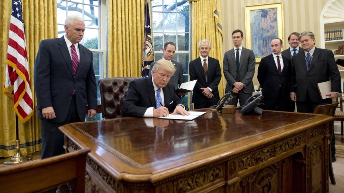 El presidente Donald Trump, junto al vicepresidente Mike Pence (izq.), firma este lunes una orden ejecutiva retirando a Estados Unidos del Acuerdo Transpacífico (TPP).