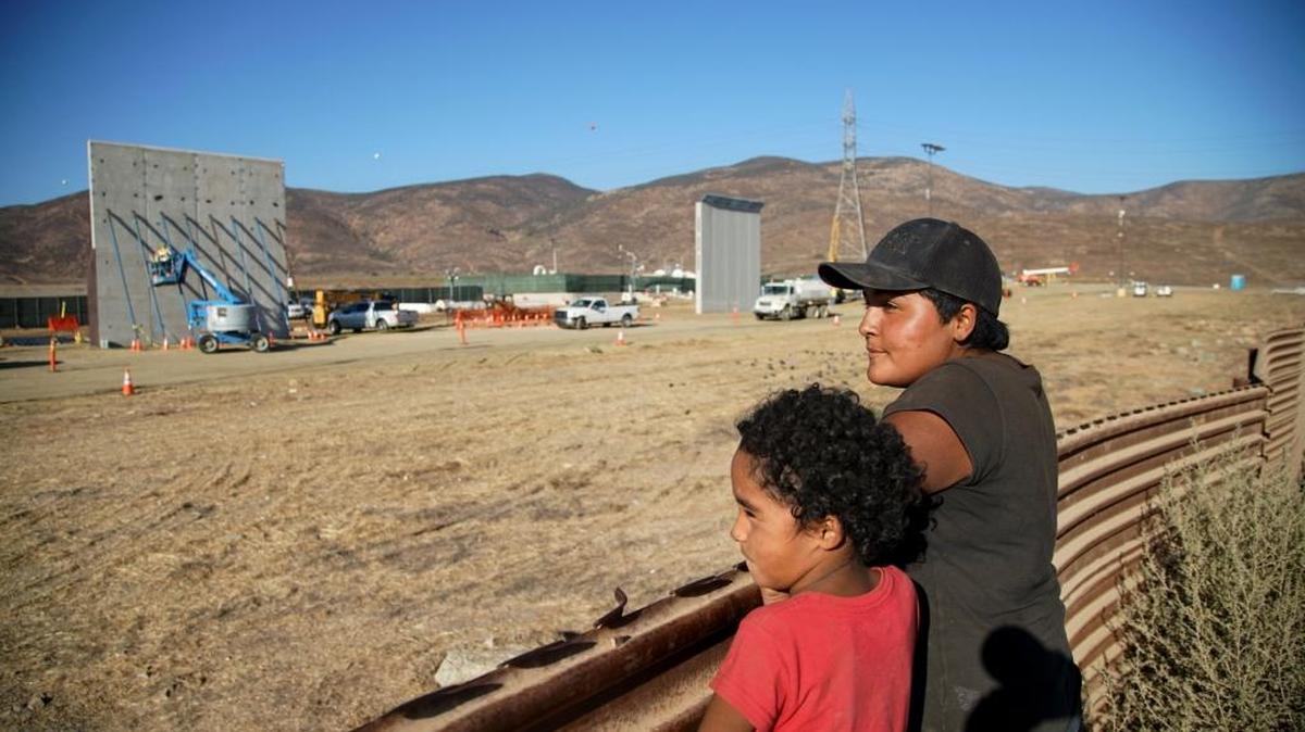 Aurelia López y su hija Antonia miran mientras trabajadores levantan prototipos de muros fronterizos, en Tijuana, México, el 5 de octubre del 2017.