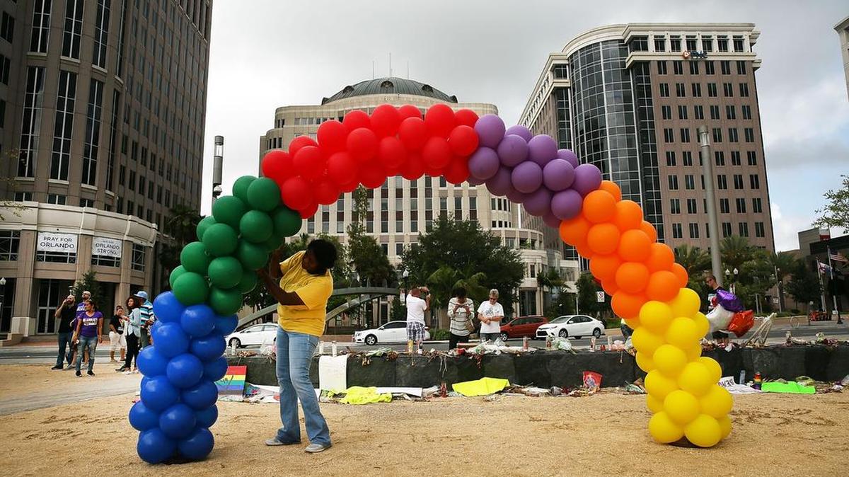 Una mujer coloca un arcoiris hecho con globos de colores atados cerca del club gay Pulse, en Orlando, el 19 de junio.