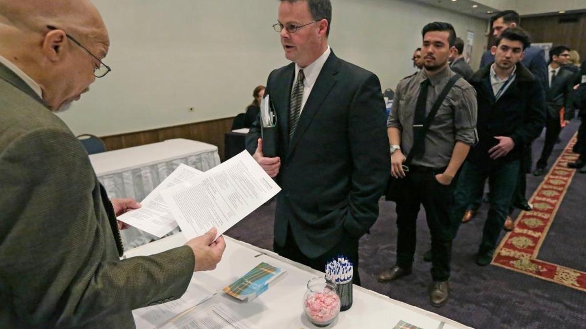 Ralph Logan, gerente general de Microtrain (izq.), atiende a personas en busca de trabajo en una feria laboral llevada a cabo en Chicago el año pasado. En marzo se crearon 215,000 empleos en todo el país.