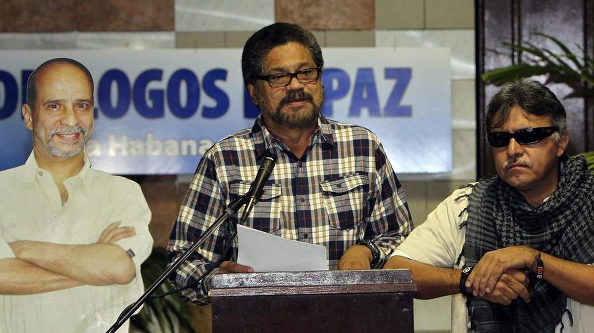 HAB02. LA HABANA (CUBA), 23/09/2014.- El segundo jefe de las Fuerzas Armadas Revolucionarias de Colombia (FARC), Luciano Marín Arango (c), alias “Iván Márquez”, lee un comunicado acompañado de su compañero Seuxis Paucias Hernández Solarte, alias “Jesús Santrich”, junto a una imagen del integrante de las FARC preso en EEUU Ricardo Palmera, alias “Simón Trinidad” (i), a su llegada hoy, martes 23 de septiembre de 2014, al Palacio de Convenciones de La Habana (Cuba). El delegados del Gobierno de colombiano y representantes de las FARC inician una nueva ronda de reuniones en el marco de las conversaciones de paz. EFE/Alejandro Ernesto