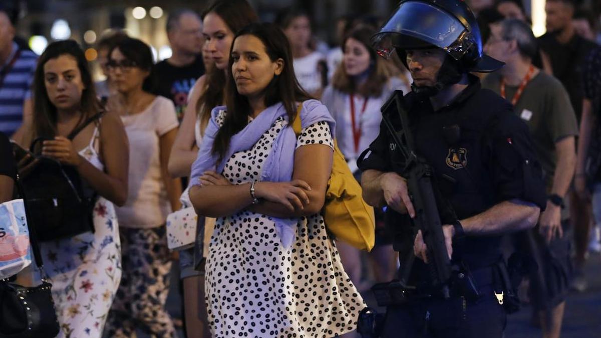 Policías sacan a un grupo de personas de un área acordonada en Barcelona, después de un acto terrorista el jueves que cobró trece vidas.
