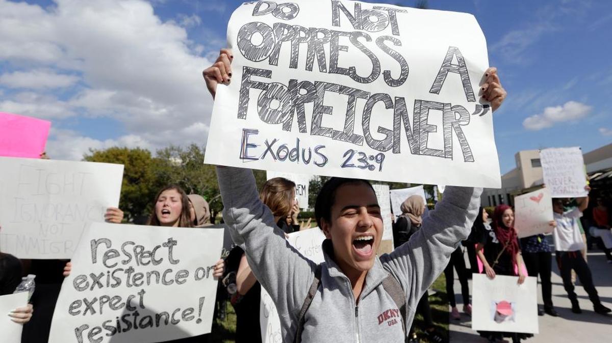Estudiantes de la Universidad Internacional de la Florida protestan contra la orden ejecutiva del presidente Donald Trump sobre inmigración el 1 de febrero. El cartel en primer plano dice: “No oprimirás al extranjero. Éxodo 23:9”. Y el segundo cartel dice: “Respeta la existencia o espera resistencia”.