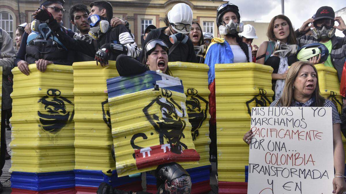 Estudiantes con escudos de fabricación cacera y otras personas protestan contra las políticas del gobierno, el 4 de diciembre de 2019, en Bogotá, Colombia.