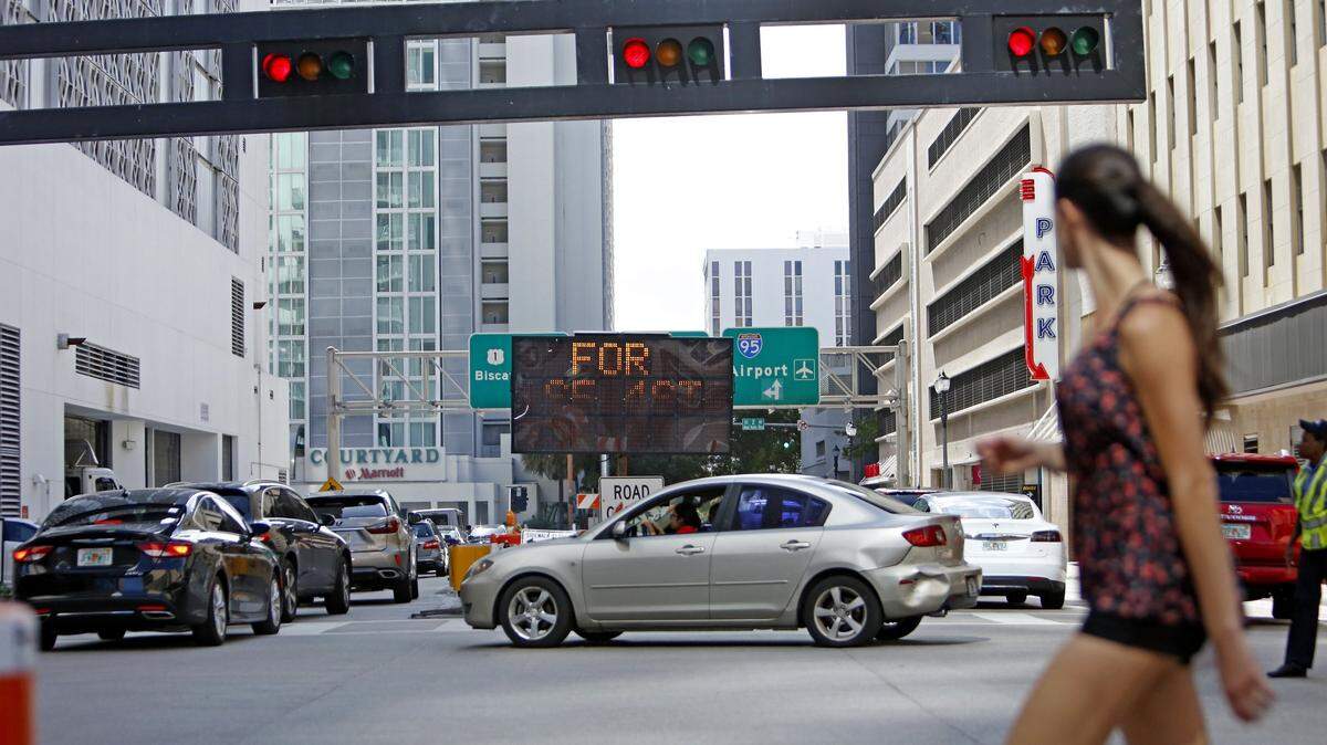 Una mujer cruza una calle en downtown Miami, el 12 de abril de 2018.