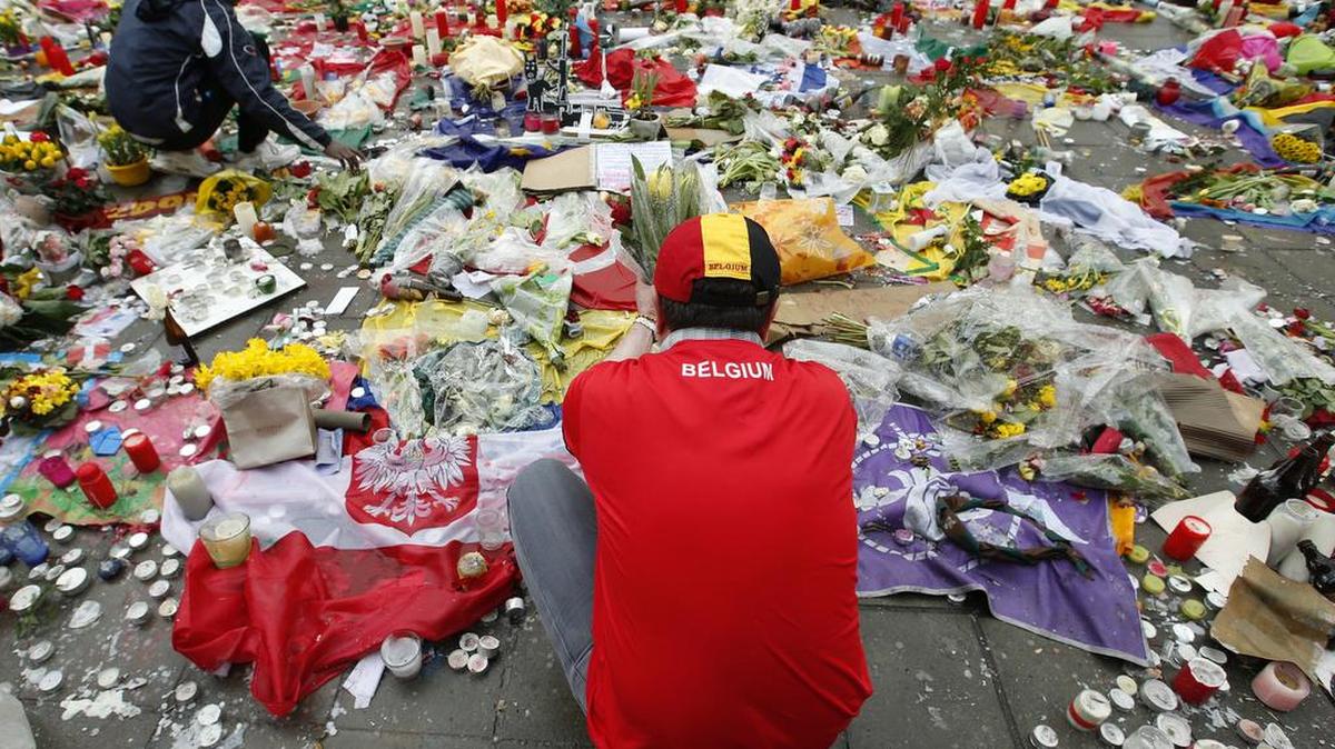 Dos hombres arreglan los tributos dejados por la gente en honor a las víctimas del atentado yihadista del pasado 28 de marzo en Bruselas.