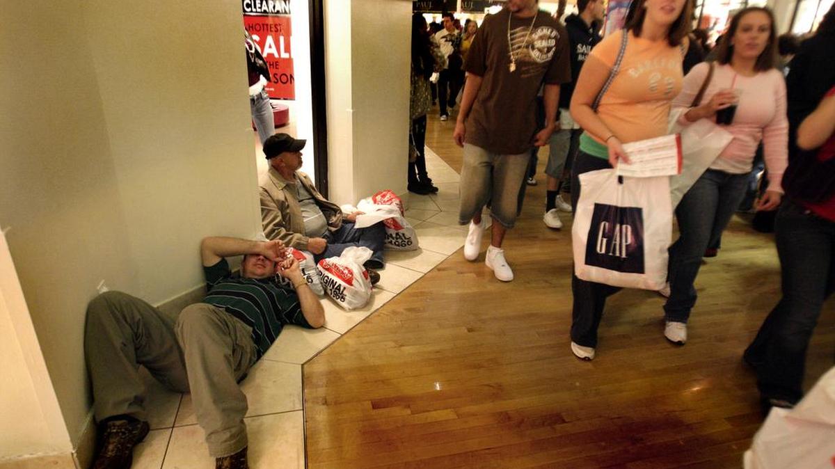 Dos hombres descansan en el piso de Sawgrass Mall, después de las correrías cazando ofertas, un ritual en temporada navideña cautivante para los nuevos residentes del Sur de Florida que intentan encajar en la cultura local consumista.