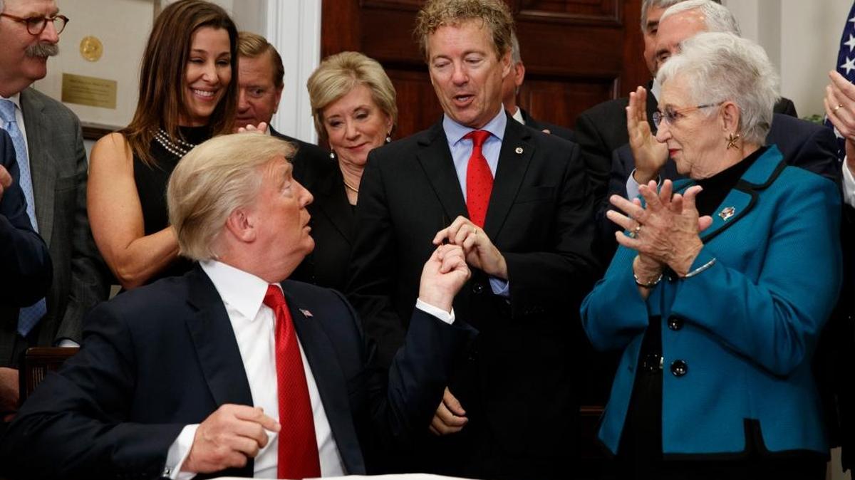 El presidente Donald Trump entrega una pluma que usó para firmar una orden ejecutiva sobre atención de la salud al senador Rand Paul, republicano por Kentucky, en el Salón Roosevelt de la Casa Blanca, el 12 de octubre.