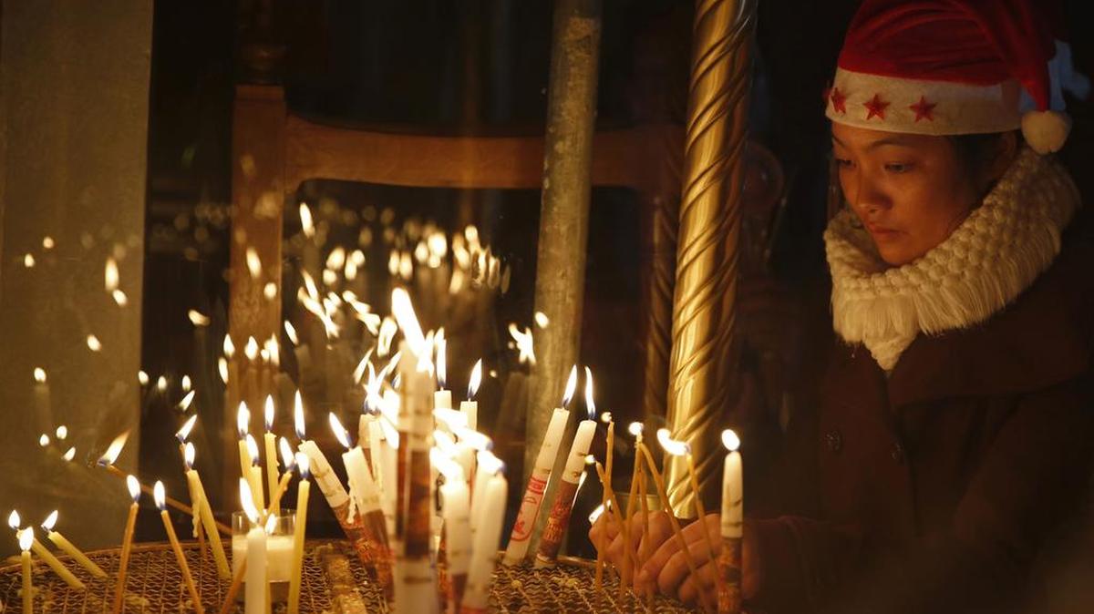 Una mujer enciende una vela en la Iglesia de la Natividad, construida en el sitio donde se cree que Jesucristo nació, en la ciudad cisjordana de Belén.