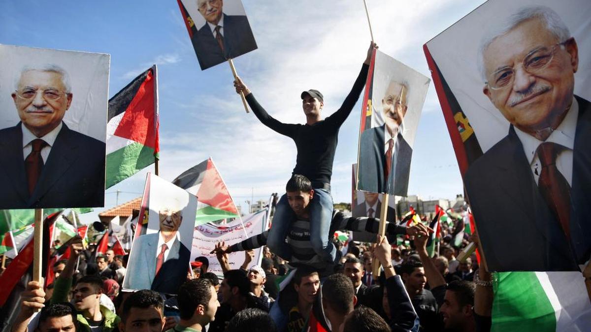 Palestinos portan fotos del presidente de Palestina, Mahmoud Abbas, mientras celebran el reconocimiento de la ONU de la condición de Estado, en Ramallah.