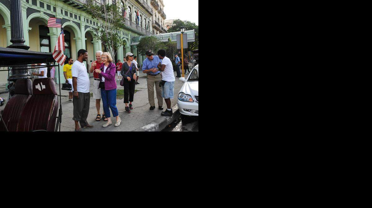 
Varios turistas hablan con el dueño de un bicitaxi que ostenta una bandera de Estados Unidos en una calle de La Habana, a fines de enero.
