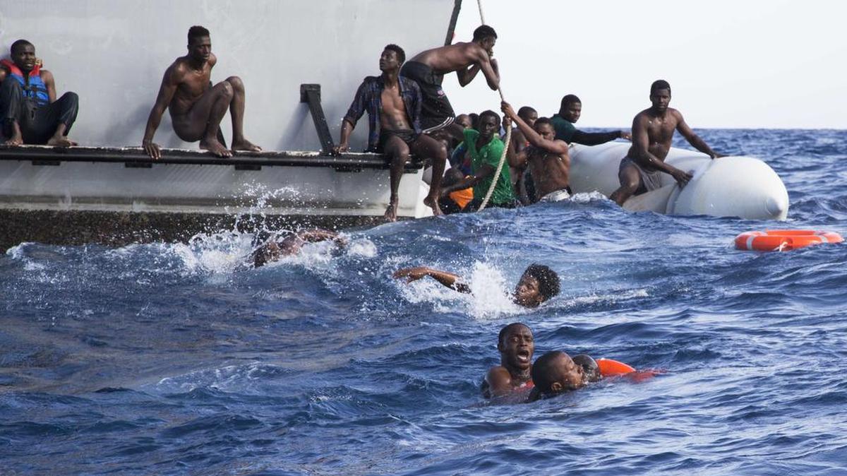 Inmigrantes africanos tratan de subir a un guardacostas libio durante una operación de rescate en el Mediterráneo, el 6 de noviembre. Cinco inmigrantes perecieron.
