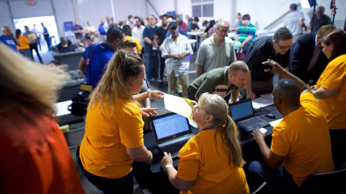 Empleados del gigante de las ventas online Amazon ayudan a personas en busca de empleo en una feria laboral de la compañía en Robbinsville, Nueva Jersey, el 2 de agosto.
