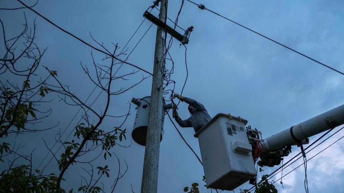 In this July 12, 2018 photo, a laborer from the Puerto Rico Power Authority works to restore power in Adjuntas, Puerto Rico. Puerto Rico’s electrical grid is still shaky after Hurricane Irma brushed past the island as a Category 5 storm last Sept. 6 and then Hurricane Maria made a direct hit as a Category 4 storm two weeks later, damaging up to 75 percent of transmission lines. (AP Photo/Dennis M. Rivera Pichardo)