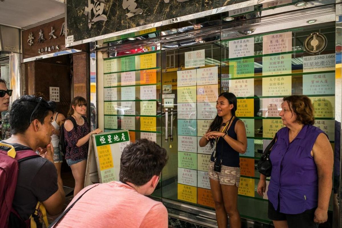 Alla Lau (segunda, der.) habla sobre la crisis de vivienda, haciendo paradas frente a agencias de bienes raíces, para hablar de la existencia de los menos favorecidos en una ciudad muy rica.