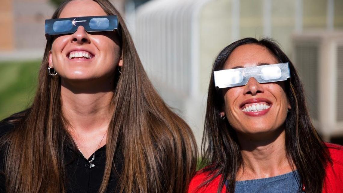 Ashley Moretti y Candace Wright, profesoras de ciencia de secundaria, usan los anteojos de protección adecuados para observar el eclipse solar, el 18 de julio, en Twin Falls, Idaho.