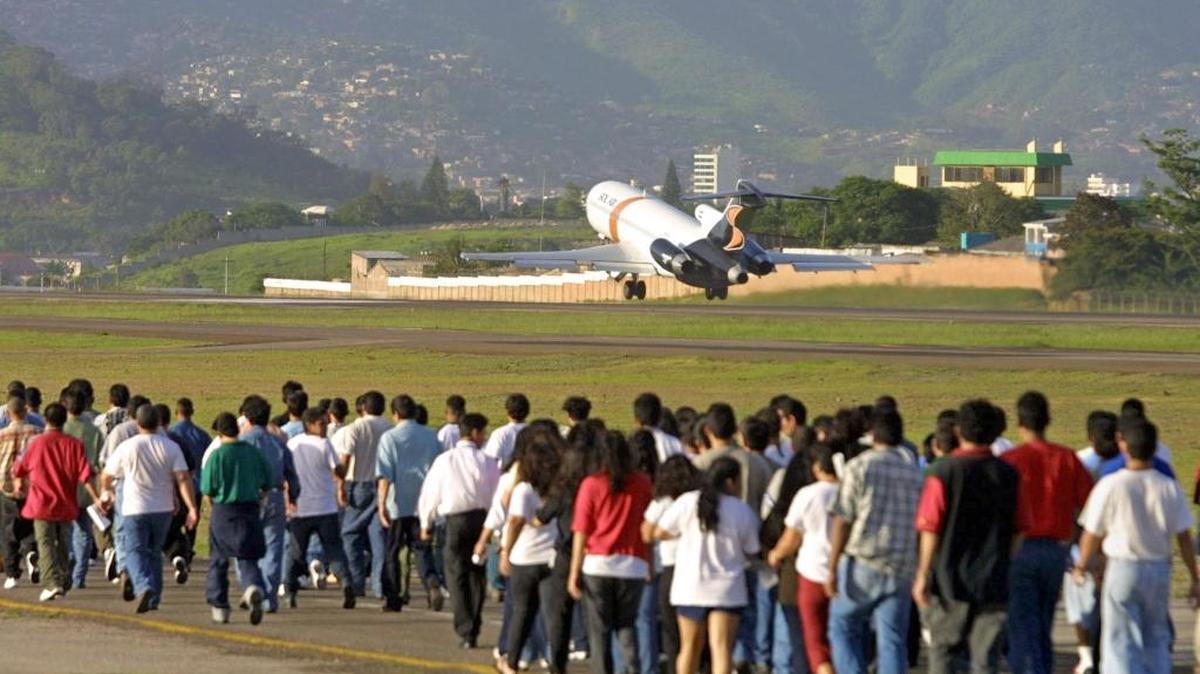 Hondureños deportados desde Estados Unidos caminan por la pista del aeropuerto Toncontín, de Tegucigalpa, que con frecuencia recibe a los migrantes irregulares expulsados de suelo estadounidense.