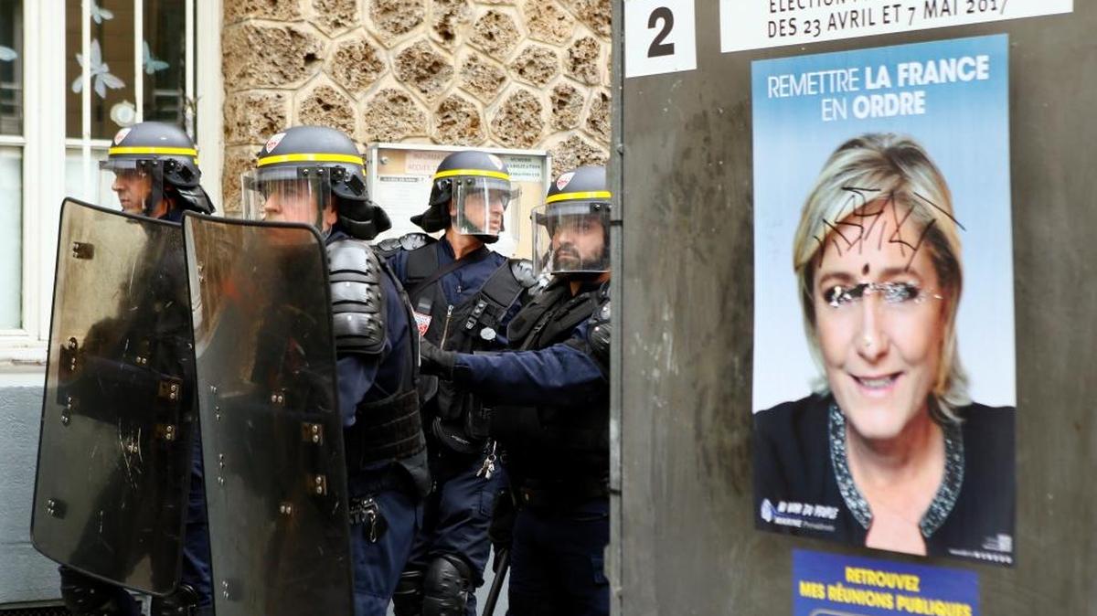 Agentes antimotines franceses se reúnen junto a un poster de Marie LePen, candidata presidencial por el ultraderechista Frente Nacional.
