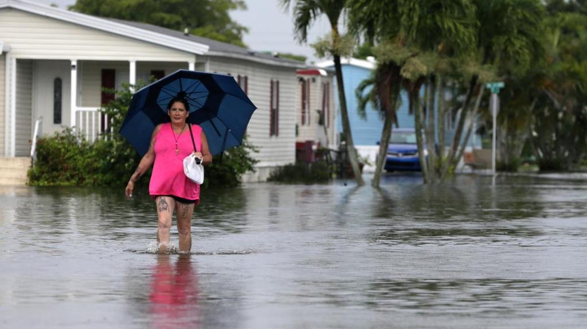 Peggy Wallace camina por una calle inundada en Davie, en junio. Los residentes de la Florida empezaron a renunciar a sus seguros cuando el Congreso aprobó un aumento en los precios en el 2012.