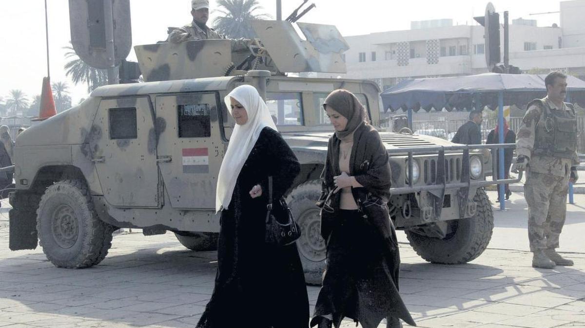 Mujeres iraquíes cruzan una intersección donde soldados iraquíes montan guardia en Bagdad, en enero del 2007.