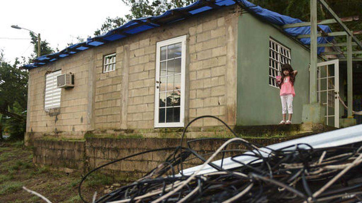 Melanie Oliveras frente a su casa y cerca de un puñado de cables eléctricos que derribaron los vientos del huracán María en Morovis, Puerto Rico.