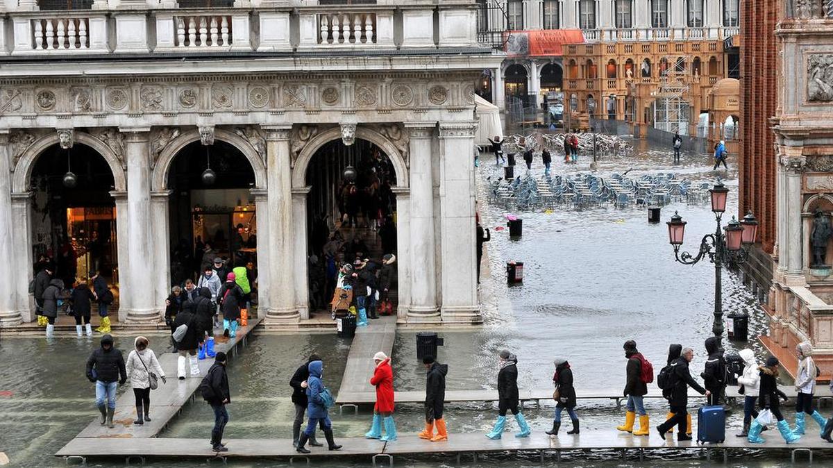 La gente camina por planchas de madera colocadas en la plaza de San Marcos, en Venecia, durante una inundación causada por la marea alta.